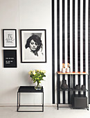 Side table and shelf against black-and-white wall with pictures on striped wallpaper