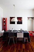 Dining table set with black tablecloth in interior with white walls and red accents of colour