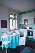 Round dining table in vintage-style kitchen in aqua shades