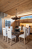 Chairs with white upholstery around glass dining table in rustic wooden house
