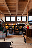 Open-plan interior of chalet with festively set table and black chairs