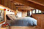 Doppelbett in weihnachtlich dekoriertem Schlafzimmer eines Chalets