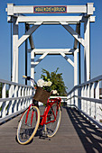 Red bicycle with hydrangeas in basket on bridge