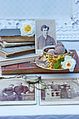 Goldene Kaffeetasse mit Pralinen und Rosenblüten, alte Bücher und Taschenuhr