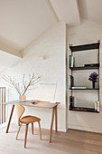 Desk and chair against whitewashed brick wall and black wall-mounted shelves