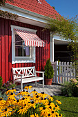 Bench below window with awning outside Falu-red Swedish house during summer
