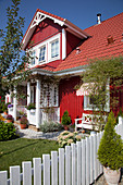 Falu-red Swedish house with porch, dormer window and sunny front garden