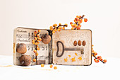 Alte Blechdose dekoriert mit Notenblatt, Eicheln, Beeren und Schlüssel