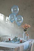 Three balloons floating above table set in pale blue and pink