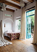 Tagesbett in Wohnraum mit hoher Holzbalkendecke und Dielenboden