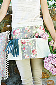 Woman wearing pretty, floral gardening apron holding hydrangeas