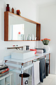 Wood-framed mirror with shelf above washstand on steel panel with copper-pipe frame