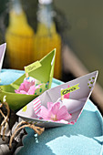 Papierschiffchen dekoriert mit Blüten als Namensschilder fürs Picknick am See