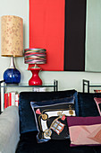 Sofa with dark seat cushions and scatter cushions in front of table lamps and wall hanging