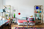Designersofa mit bunten Kissen, offene Regale und Couchtisch im Wohnzimmer in 70er Jahre-Stil