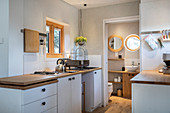 Küchenbereich mit weißen Schränken und Holzarbeitsplatten in Tiny House