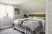 Pretty bedroom with patterned wallpaper and crocheted blanket on double bed