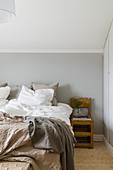 Doppelbett und Nachttisch im Schlafzimmer mit hellgrauer Wand