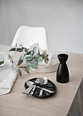 Cutlery, carafe and eucalyptus branch on table