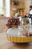Hydrangea and sugar bowl in yellow tart dish used as tray