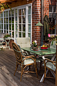 Rattan chair around garden table on terrace of brick house