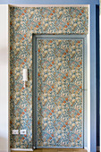 Door and niche covered in floral wallpaper in shades of blue and orange