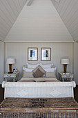 White rattan with lamps on bedside tables below gable ceiling in beach house