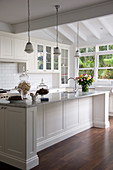 Glass vessels on white kitchen counter below pendant lamps