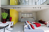 Offener Wohnraum in Architektenhaus mit Galerie und gelben Schrankwänden als Raumtrenner