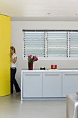 Grey-and-white kitchen counter and yellow floor-to-ceiling cupboard in architect-designed house