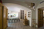 Blick in weiße Landhausküche mit Fliesenboden und Hockern an Frühstückstheke