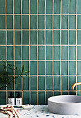 Vanity with hand basin against green tiled wall