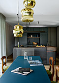 Metal dining table with blue top in front of modern kitchen in shades of grey