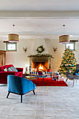 Christmas tree and blue and red furnishings in front of open fireplace