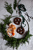 Christmas wreath, tangerine, scissors and gingerbread pretzels