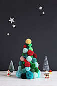 Christmas tree made from colourful pompoms against black wall