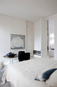 White bedroom with pale blue accents and black armchair