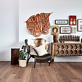 Ethnic accessories on wall above rattan armchair and console table