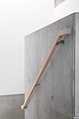 Simple wooden handrail on concrete wall