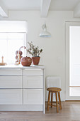 Terracotta pots on white kitchen counter and wooden stool