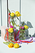 Double tulips in screw-top jars decorated with colourful ribbons
