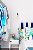 Bed with blue-and-white striped headboard, bedside table and clothes rail