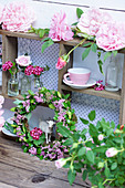 Kranz aus Spierstrauch-Blüten, Nelken in Fläschchen und Rosenblüten