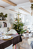 Gedeckter Tisch und Weihnachtsbaum im offenen Wohnraum