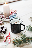 Hot drink in enamel mug, sweets and fir branch