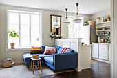 Blaues Sofa an der Raumteilerwand zur offenen Küche