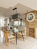 Glass dining table and brick fireplace in open-plan kitchen