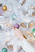 Einen weissen Tannenbaum mit Weihnachtskugeln dekorieren