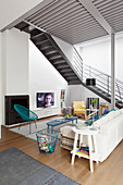 Sofa, easy chairs and TV in seating area below steel staircase in loft apartment