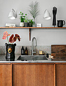 Bären-Vase mit Flamingoblumen neben der Spüle in rustikaler Küche